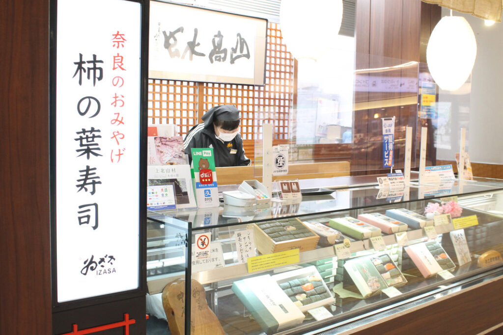 東改札前のゐざさ東売店と柿の葉寿司のパッケージ